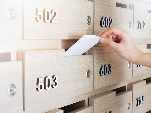 Close-up of person's hand . hand removing a letter from mailbox in the entrance hall of an apartment building Photo of a mail box with a hand pulling out a letter.